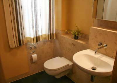 WC mit Lehmputz und Naturstein-Fliesen