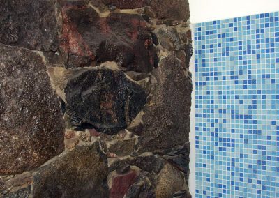Zusammenspiel von Mosaikfliesen und Feldsteinmauerwerk im Bad