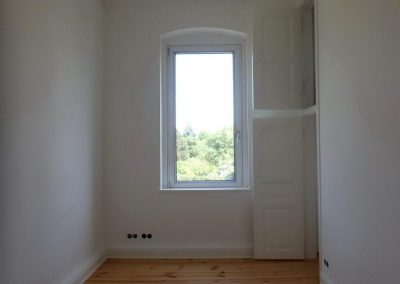 Zimmer mit Altbau-Kammertüren und aufgearbeiteten Decken- und Wandflächen